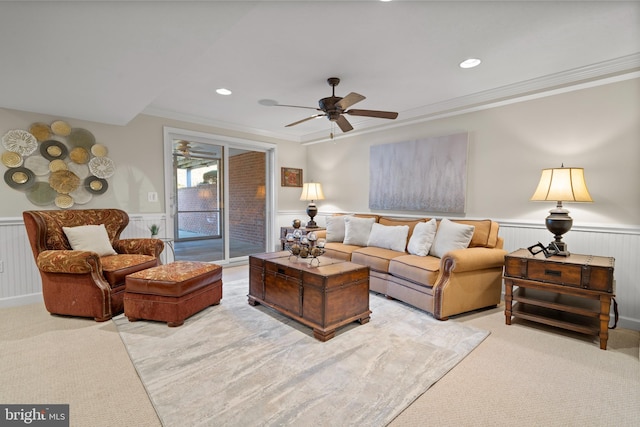 living room with ceiling fan, crown molding, and light colored carpet