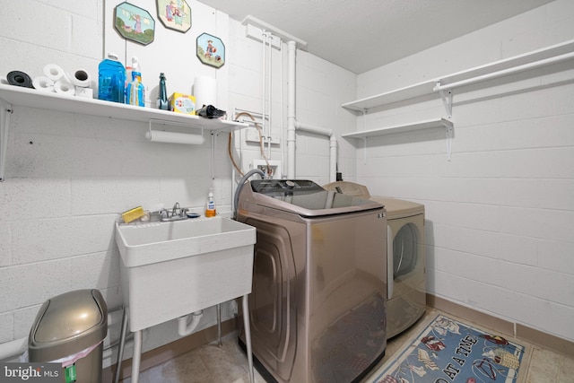 washroom with sink, a textured ceiling, and washer and clothes dryer