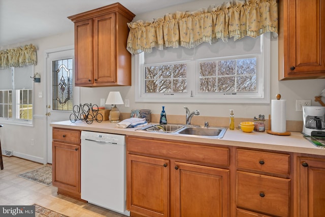 kitchen featuring plenty of natural light, white dishwasher, sink, and light tile flooring