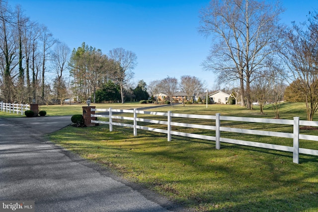 view of gate with a rural view and a lawn