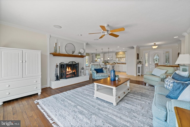 living room featuring crown molding, dark hardwood / wood-style floors, a fireplace, and ceiling fan