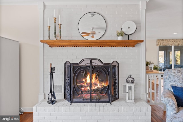 interior details with hardwood / wood-style floors, crown molding, ceiling fan, and a brick fireplace