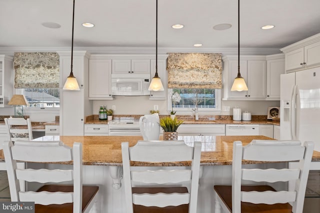 kitchen with white appliances, light stone countertops, decorative light fixtures, and a kitchen breakfast bar