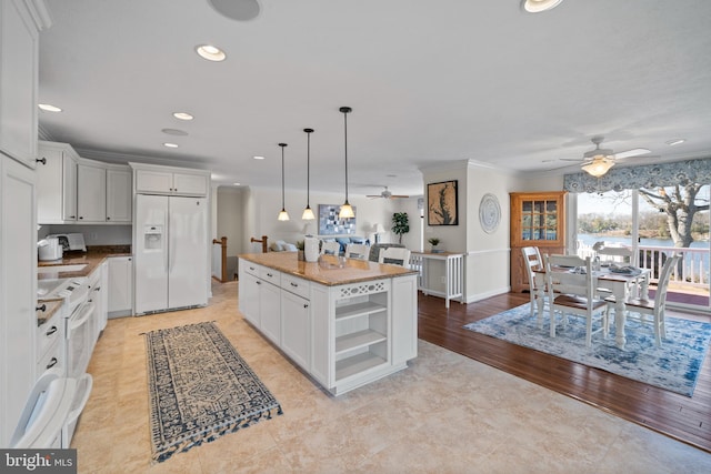 kitchen featuring pendant lighting, ceiling fan, light stone counters, white fridge with ice dispenser, and a center island