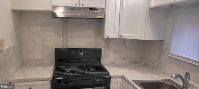 kitchen with tasteful backsplash, range, white cabinetry, and light stone counters