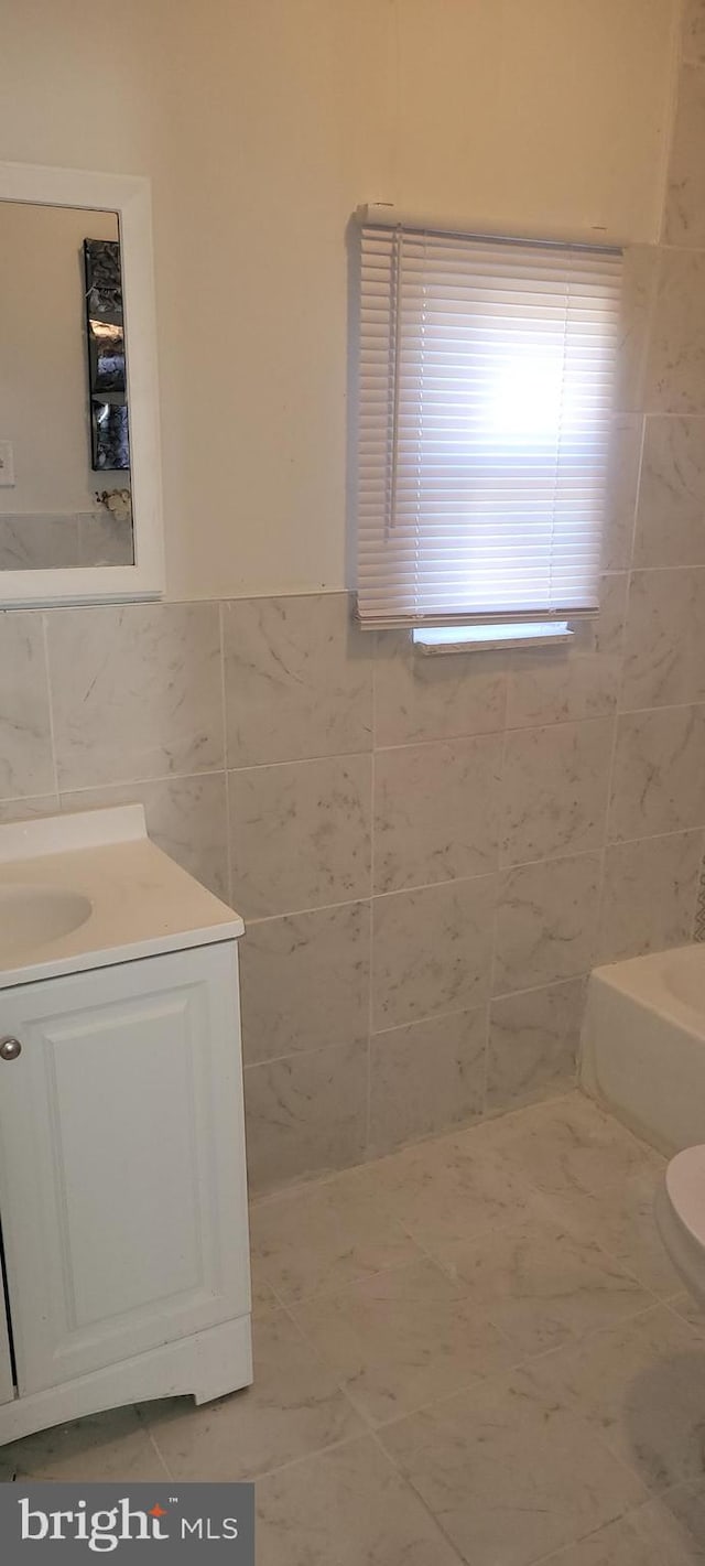 bathroom with tile floors, tile walls, toilet, and vanity