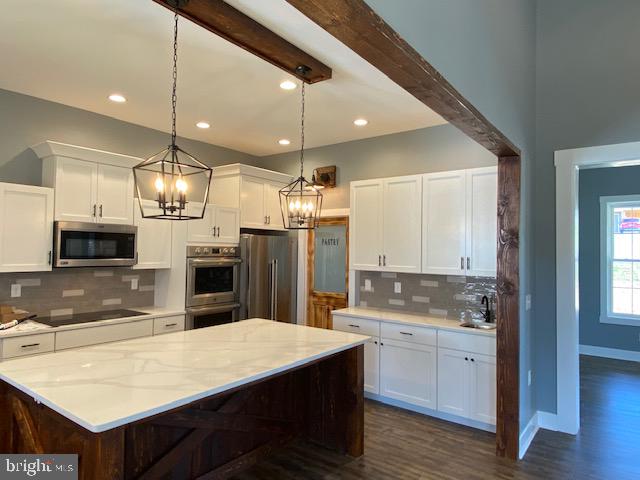 kitchen featuring decorative backsplash, white cabinets, dark hardwood / wood-style flooring, appliances with stainless steel finishes, and decorative light fixtures