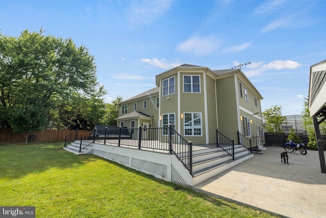 rear view of property featuring a patio, a deck, and a lawn