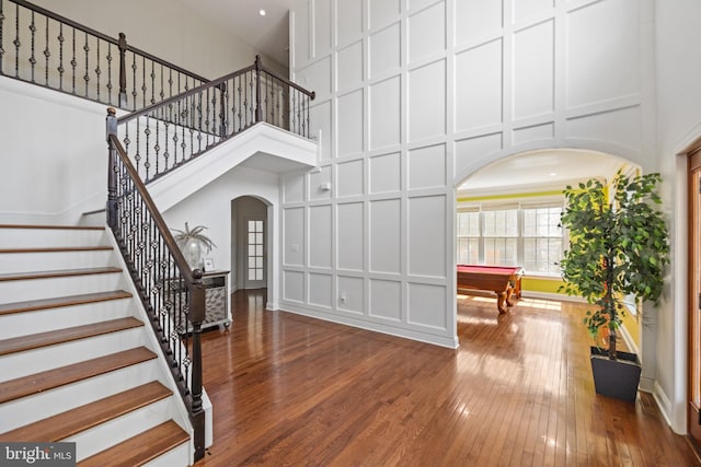 staircase featuring hardwood / wood-style flooring, a towering ceiling, and billiards