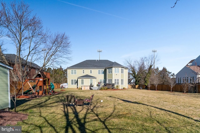 rear view of property with a playground and a yard