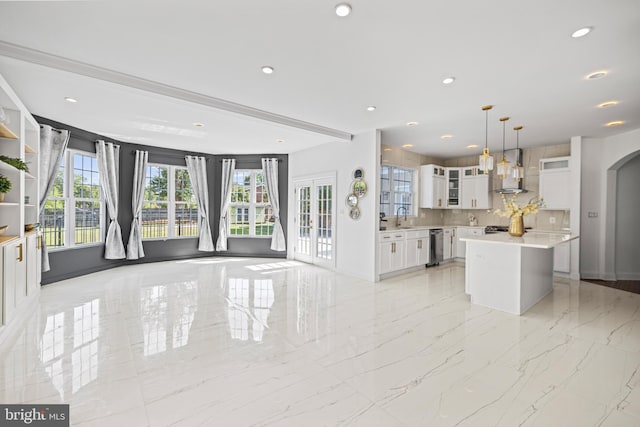 kitchen with a kitchen island, backsplash, hanging light fixtures, wall chimney exhaust hood, and white cabinets