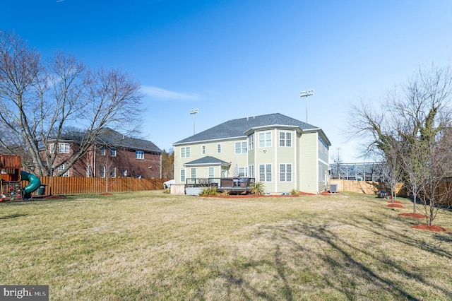 back of house featuring a playground, a deck, and a yard