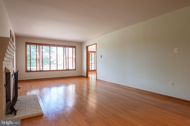 unfurnished living room featuring a brick fireplace and light hardwood / wood-style floors