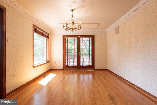 spare room with crown molding, hardwood / wood-style flooring, and an inviting chandelier