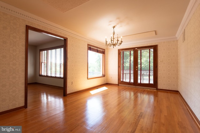 spare room with a notable chandelier, crown molding, and hardwood / wood-style flooring