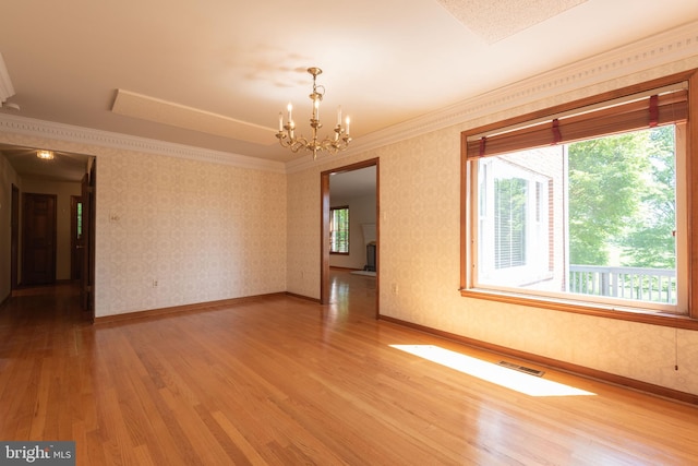 unfurnished room with crown molding, an inviting chandelier, and hardwood / wood-style floors