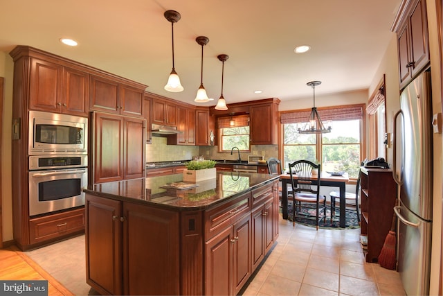 kitchen featuring hanging light fixtures, stainless steel appliances, tasteful backsplash, and light tile flooring