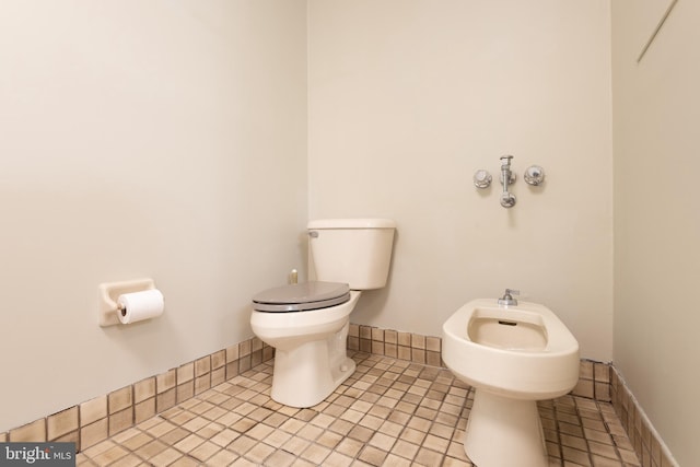 bathroom with a bidet, tile floors, and toilet