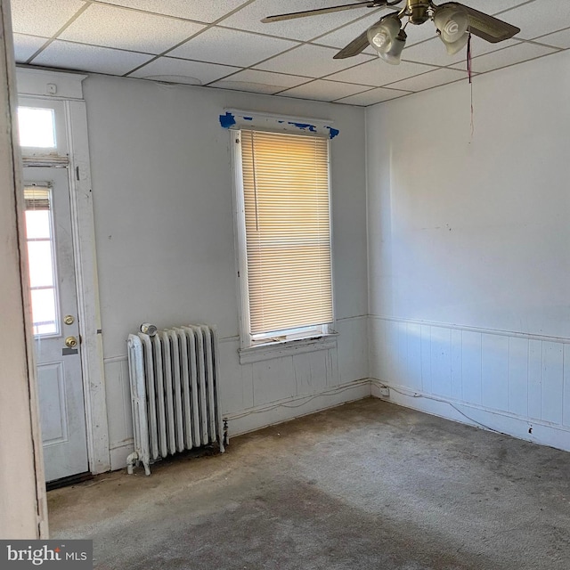 carpeted empty room featuring radiator heating unit, a paneled ceiling, and ceiling fan