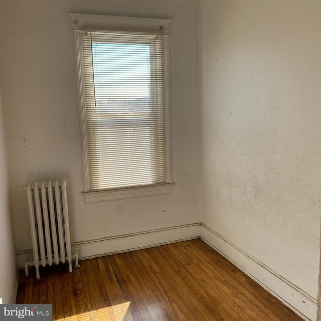 spare room featuring radiator and dark wood-type flooring