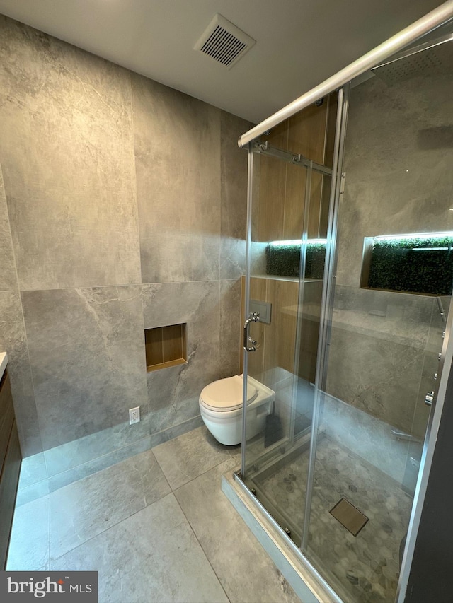 bathroom with vanity, tile walls, tile floors, a shower with door, and toilet