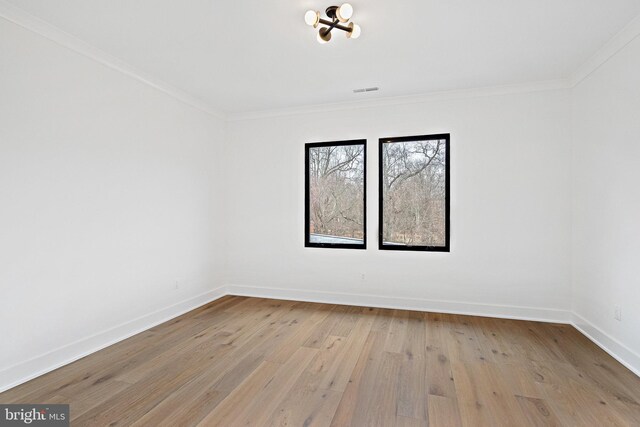 empty room with crown molding and light hardwood / wood-style floors