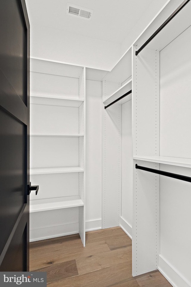 walk in closet with light hardwood / wood-style flooring