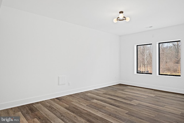 empty room featuring dark wood-type flooring and a chandelier