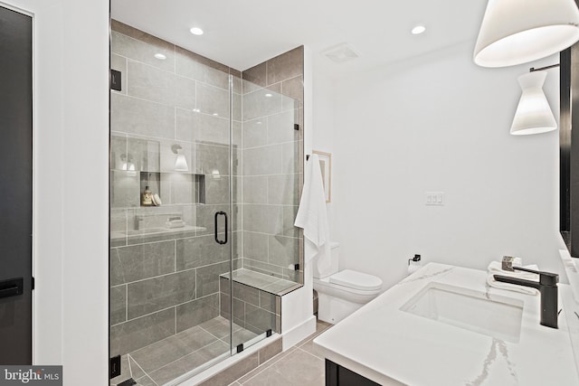 bathroom with tile patterned floors, vanity, an enclosed shower, and toilet