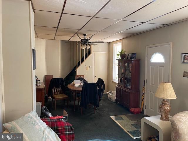 dining space with a paneled ceiling, dark carpet, and ceiling fan