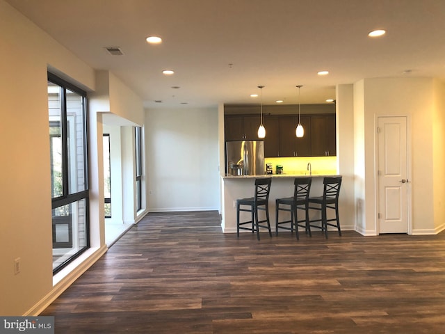 kitchen featuring dark brown cabinetry, stainless steel fridge with ice dispenser, kitchen peninsula, a kitchen breakfast bar, and wood-type flooring