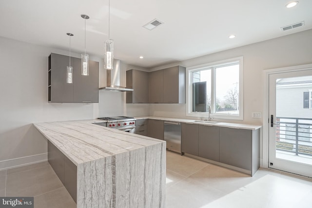 kitchen with appliances with stainless steel finishes, a healthy amount of sunlight, decorative light fixtures, and kitchen peninsula