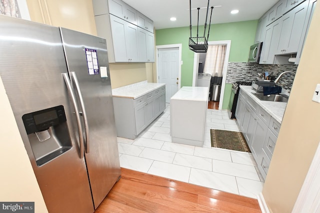 kitchen featuring sink, stainless steel appliances, a center island, tasteful backsplash, and pendant lighting