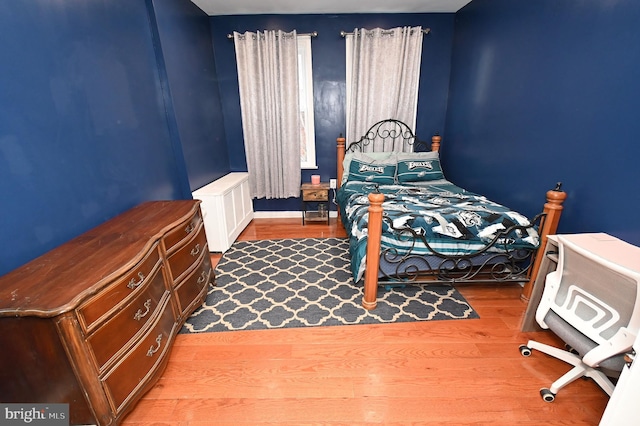 bedroom with radiator heating unit and hardwood / wood-style floors