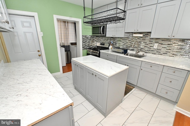 kitchen featuring gray cabinetry, appliances with stainless steel finishes, sink, a kitchen island, and tasteful backsplash