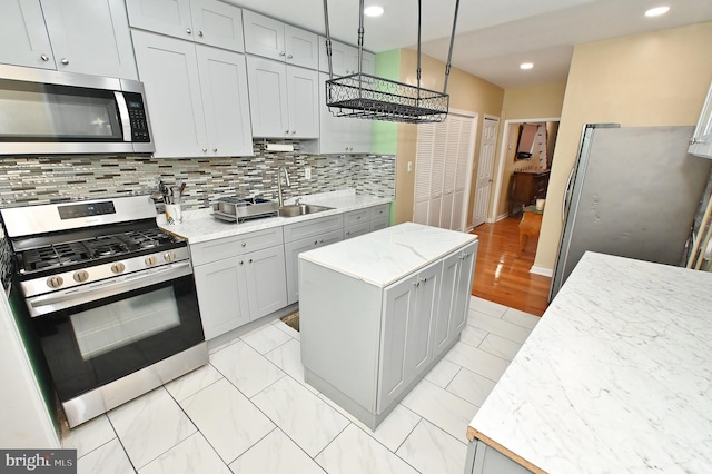 kitchen featuring appliances with stainless steel finishes, a center island, gray cabinets, backsplash, and light tile flooring