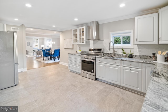 kitchen with white cabinetry, stainless steel appliances, ornamental molding, wall chimney exhaust hood, and sink