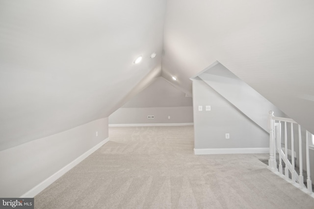 additional living space featuring vaulted ceiling and light colored carpet