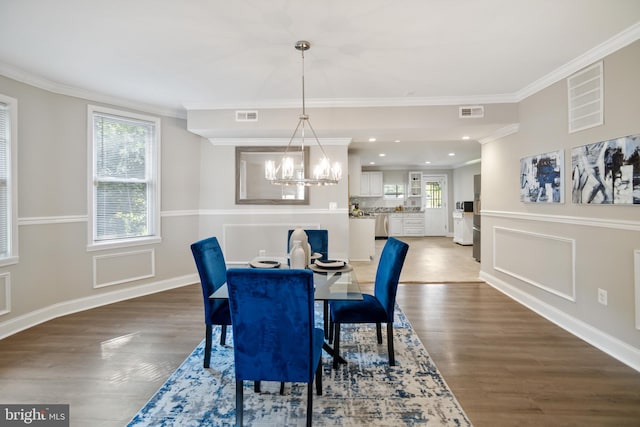 dining area with dark hardwood / wood-style flooring, crown molding, and a notable chandelier