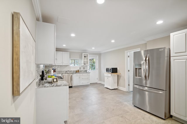 kitchen with light stone counters, white cabinetry, ornamental molding, and stainless steel appliances