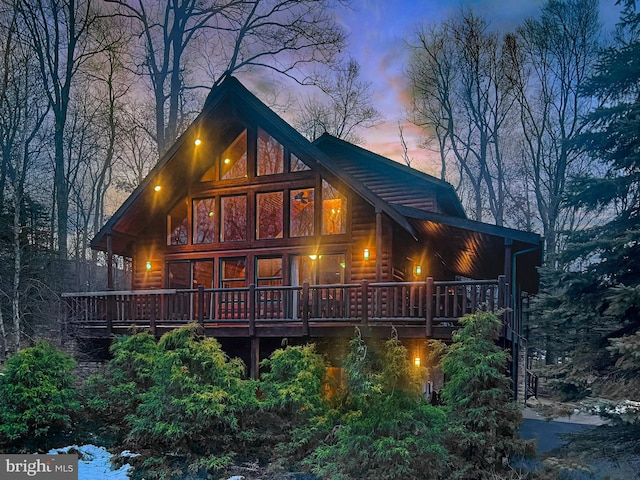 back house at dusk featuring a wooden deck