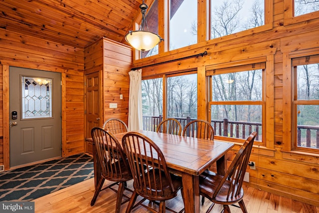 dining space featuring wood ceiling, a healthy amount of sunlight, wood walls, and light wood-type flooring