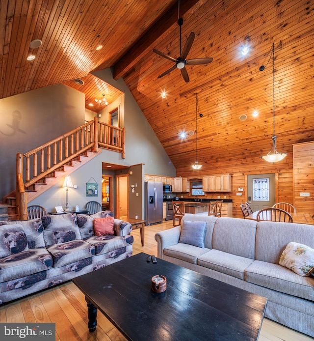 living room featuring wood walls, high vaulted ceiling, light hardwood / wood-style floors, and ceiling fan