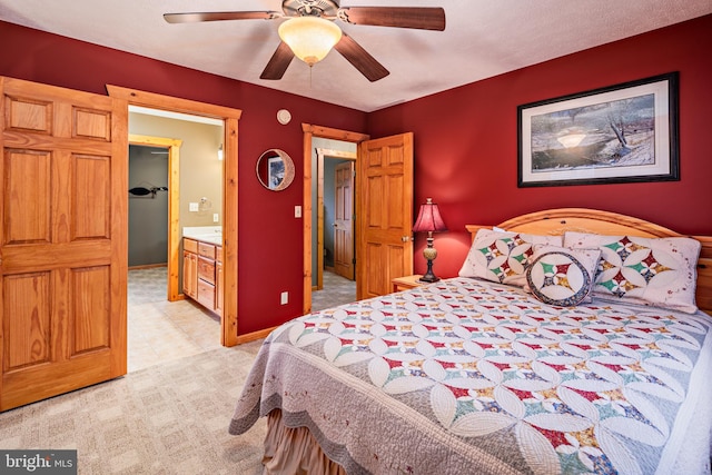 bedroom featuring light carpet, ensuite bathroom, and ceiling fan