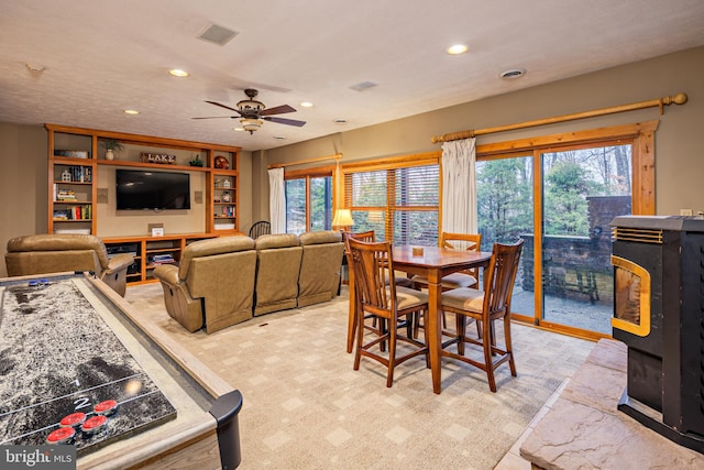 dining area with ceiling fan and a wood stove