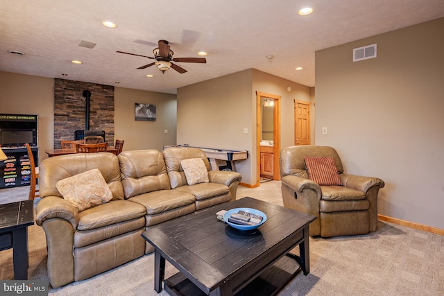 carpeted living room featuring a textured ceiling, ceiling fan, and a wood stove