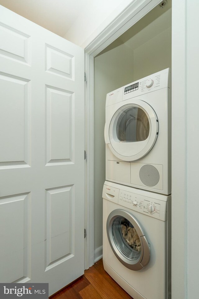 washroom featuring wood-type flooring and stacked washer / dryer