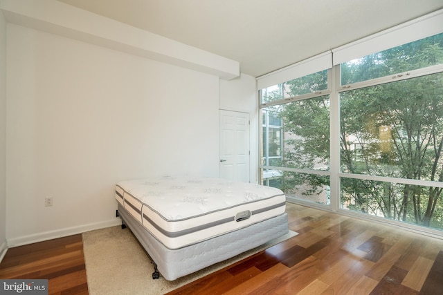 unfurnished bedroom featuring a wall of windows and hardwood / wood-style flooring