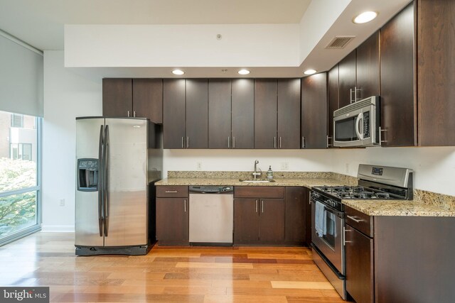 kitchen featuring dark brown cabinetry, sink, light hardwood / wood-style floors, and stainless steel appliances