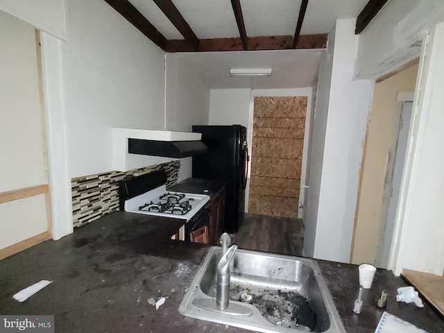 kitchen with sink, black fridge, beamed ceiling, white range with gas stovetop, and backsplash